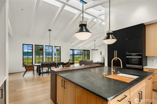 a kitchen with stainless steel appliances kitchen island a table chairs in it and wooden floors