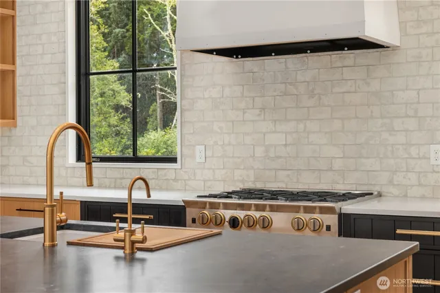 a kitchen with stainless steel appliances granite countertop a sink a stove and a wooden floors