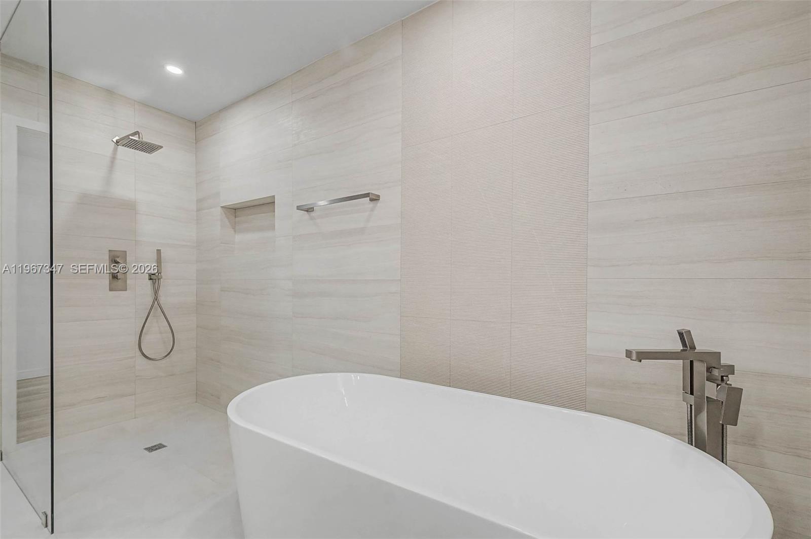 12940 Southwest 73rd Avenue Pinecrest, FL 33156 - Photo 14 of 38 a bathroom with a white bath tub and a shower