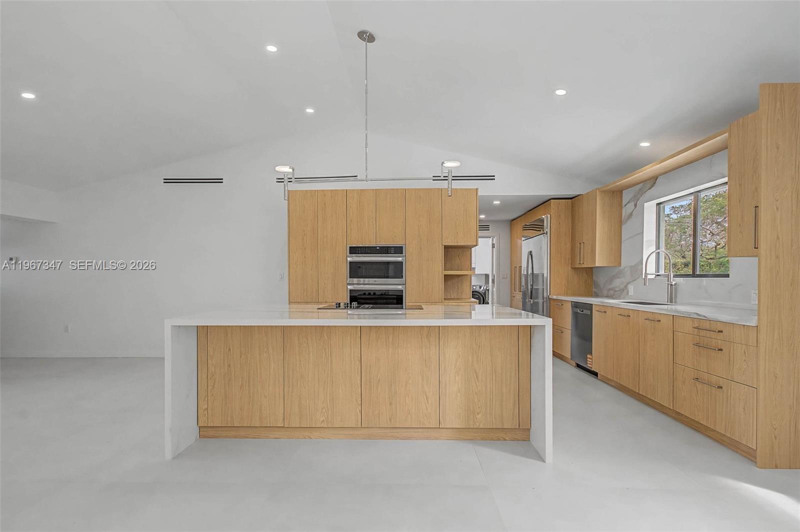 12940 Southwest 73rd Avenue Pinecrest, FL 33156 - Photo 8 of 38 a large kitchen with stainless steel appliances a large counter top a stove a sink dishwasher a refrigerator and white cabinets with wooden floor