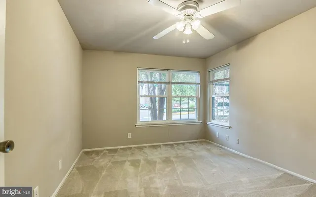 an empty room with a chandelier fan and windows