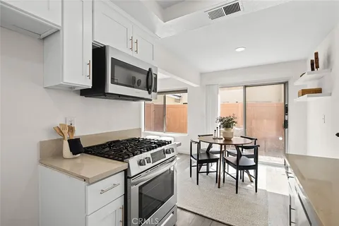 a kitchen with stainless steel appliances kitchen island a white stove top oven a sink dishwasher and white cabinets with wooden floor