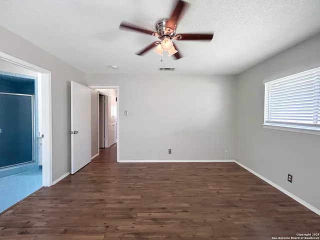 an empty room with fan and windows