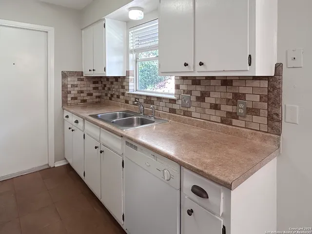 a kitchen with granite countertop a sink and white cabinets