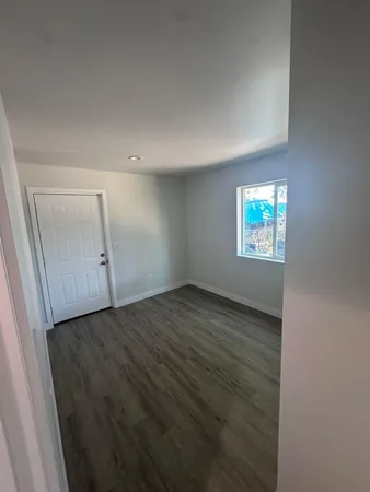 an empty room with wooden floor cabinet and windows
