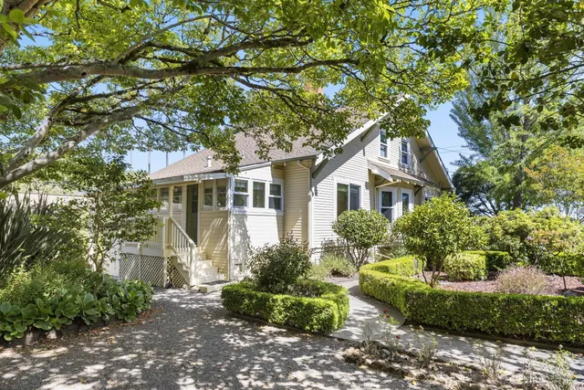 a front view of a house with a yard and potted plants