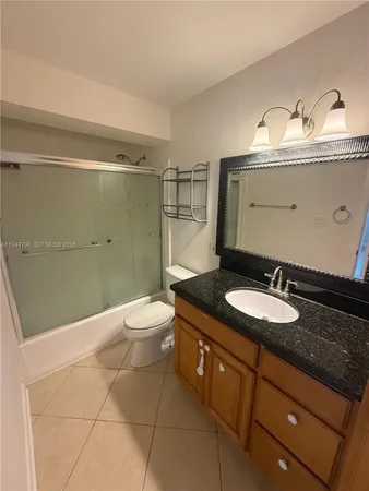a bathroom with a granite countertop sink toilet and mirror