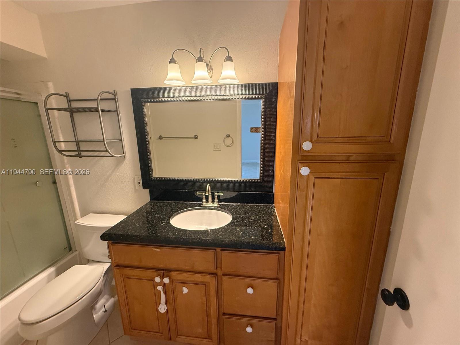 15581 Southwest 104th Terrace, Unit 222 Miami, FL 33196 - Photo 14 of 23 a bathroom with a granite countertop sink toilet and mirror