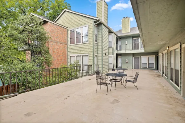 a patio with a table and chairs and potted plants