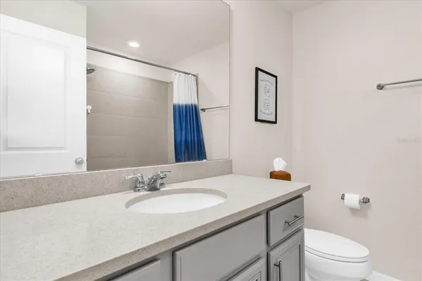 a bathroom with a granite countertop sink a toilet and a mirror