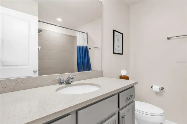 a bathroom with a granite countertop sink a toilet and a mirror