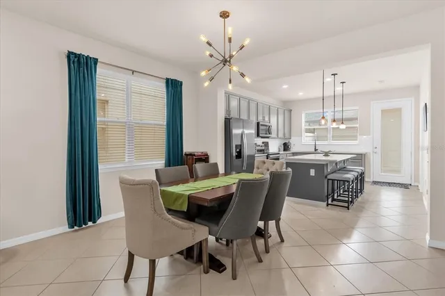 a dining room with kitchen island stainless steel appliances furniture a window and kitchen view