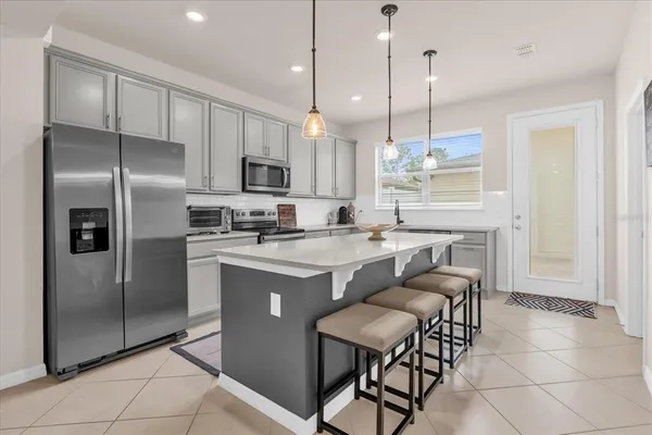 a kitchen with stainless steel appliances granite countertop a refrigerator a sink a stove a dining table and chairs