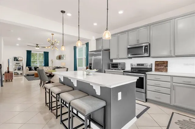 a kitchen with stainless steel appliances kitchen island granite countertop a stove a sink a oven a dining table and chairs