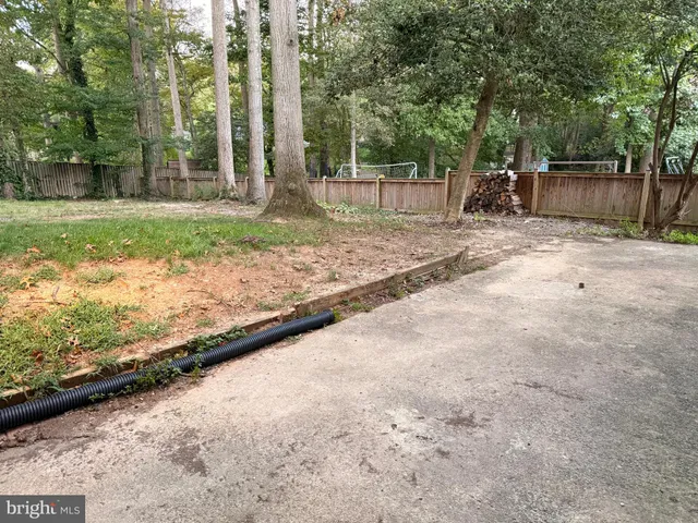 a backyard of a house with a large tree and wooden fence