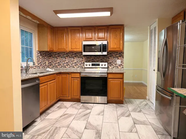 a kitchen with stainless steel appliances granite countertop a stove a refrigerator and a sink