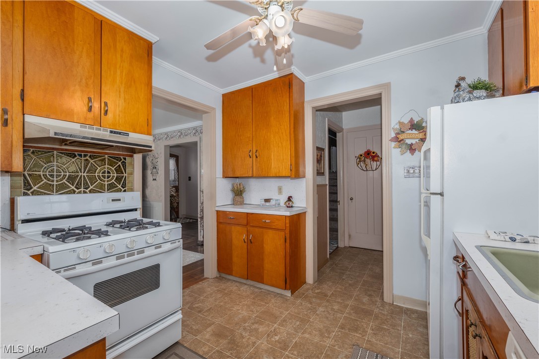 915 Raff Road Southwest Canton, OH 44710 - Photo 9 of 25 Kitchen featuring crown molding, decorative backsplash, ceiling fan, and white appliances