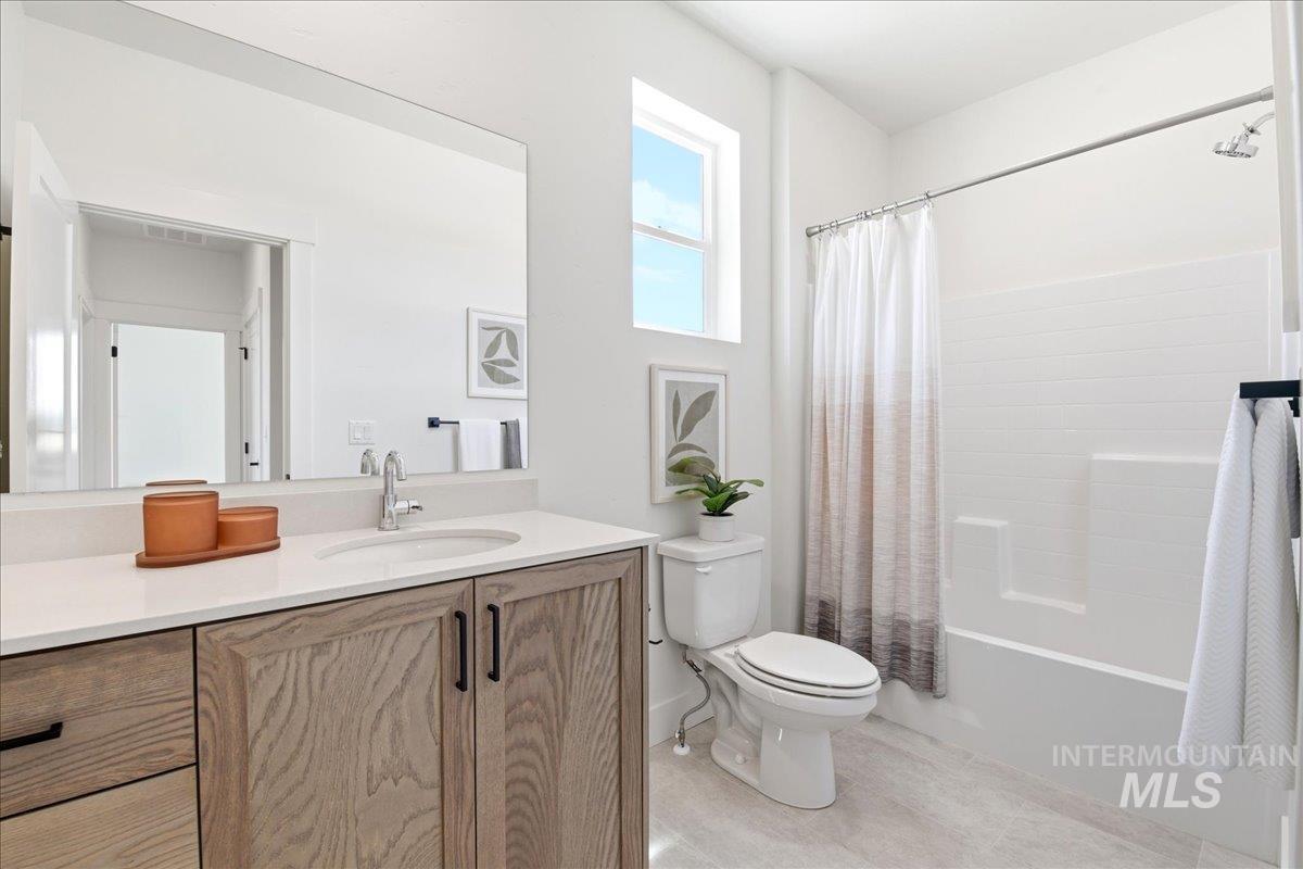 3405 Elliptical Lane Caldwell, ID 83607 - Photo 10 of 17 Bathroom featuring a light wood-finish vanity with a white countertop and undermount sink, a large wall-mounted mirror, a tub and shower combination with white subway-style tile, and a single window