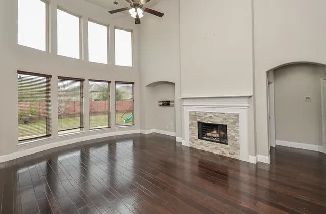 a view of an empty room with wooden floor fireplace and a window