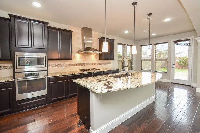 a large kitchen with stainless steel appliances granite countertop a stove a sink and a refrigerator