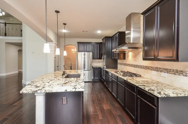 a kitchen with stainless steel appliances kitchen island granite countertop a sink stove and refrigerator