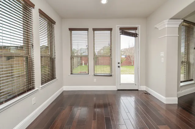 a view of an empty room with wooden floor and a window