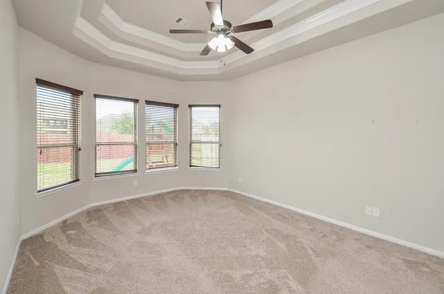 an empty room with chandelier fan and windows