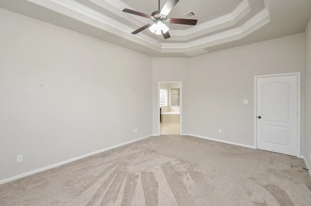 a view of an empty room and chandelier fan