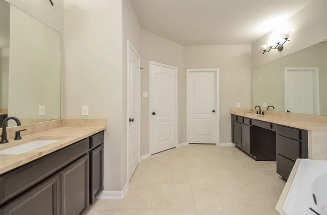 a spacious bathroom with a double vanity sink a mirror and a bathtub