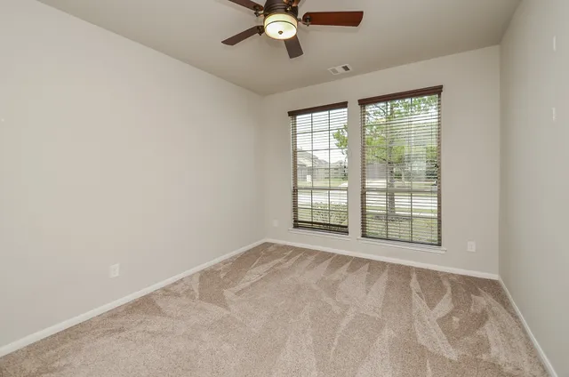 an empty room with windows and fan