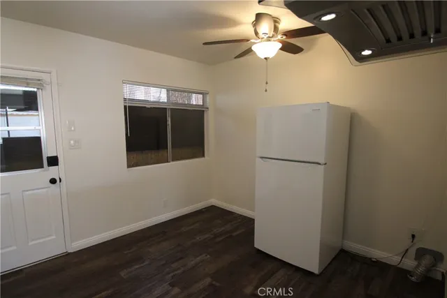 an empty room with wooden floor and ceiling fan