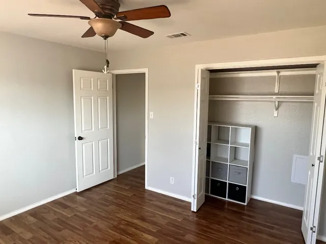 a view of empty room with wooden floor and fan