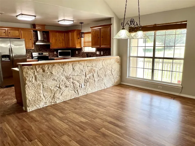 a kitchen with granite countertop a stove a sink and a refrigerator