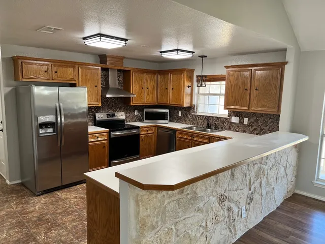 a kitchen with stainless steel appliances granite countertop a sink a stove and a refrigerator