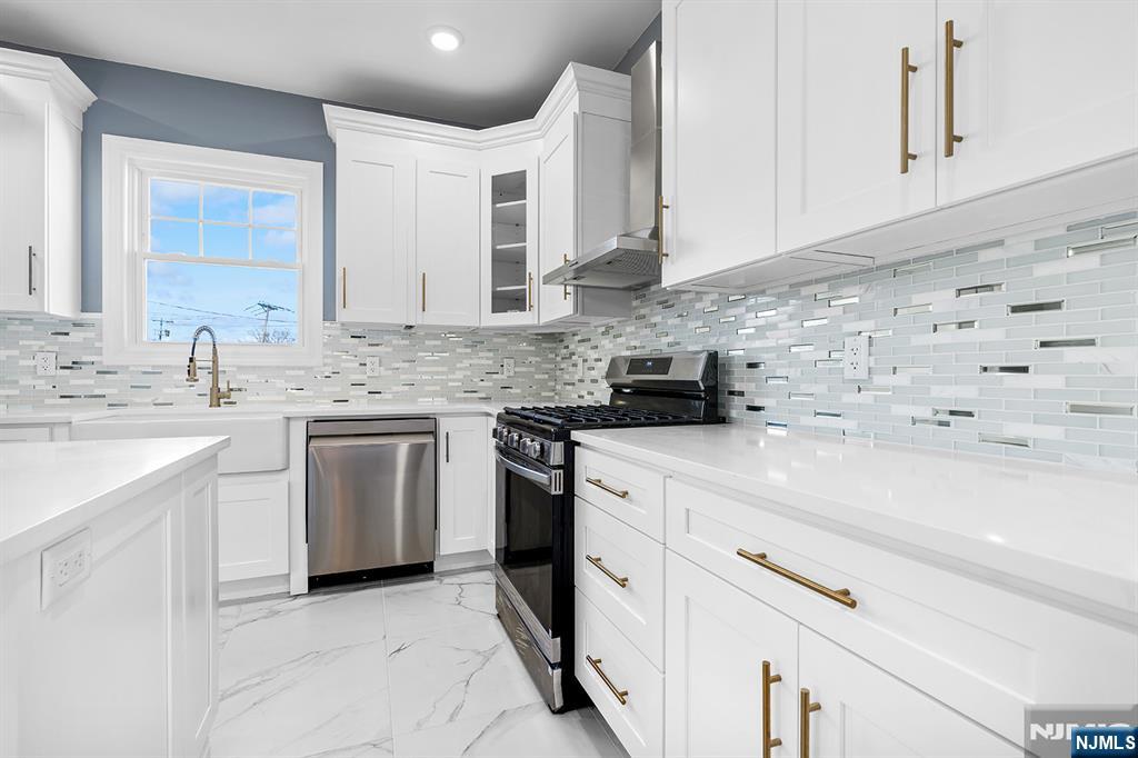 255 Garibaldi Avenue Lodi, NJ 07644 - Photo 8 of 34 a kitchen with stainless steel appliances granite countertop a sink stove a refrigerator and white cabinets