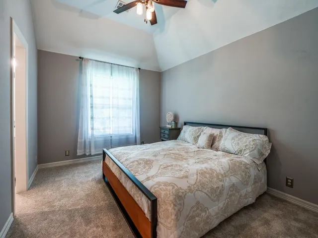 a bed sitting in a spacious bedroom next to a window