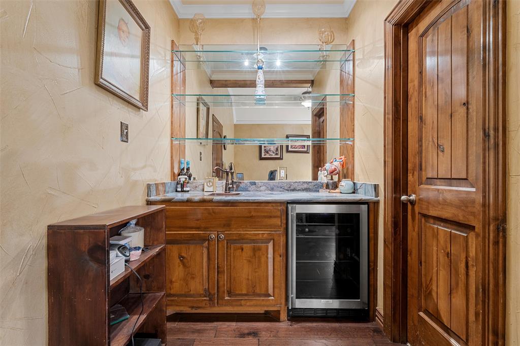 1125 Whispering Oaks China Spring, TX 76633 - Photo 18 of 39 Indoor wet bar with brown cabinetry, beverage cooler, dark wood-style floors, crown molding, and light countertops