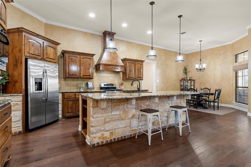 1125 Whispering Oaks China Spring, TX 76633 - Photo 2 of 39 Kitchen featuring light stone counters, tasteful backsplash, ornamental molding, decorative light fixtures, and a kitchen island with sink