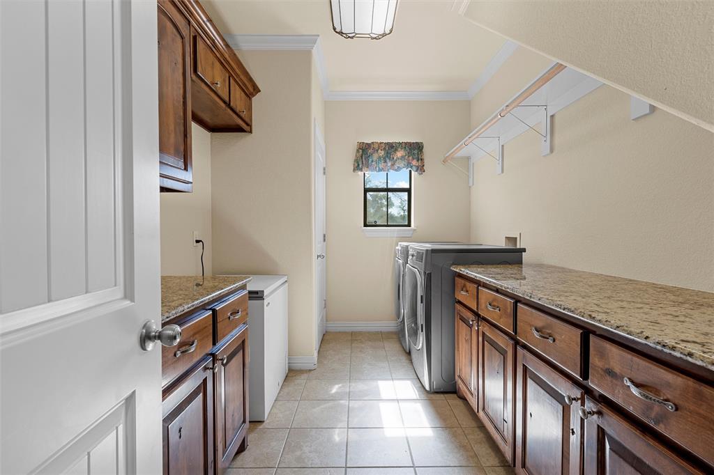 1125 Whispering Oaks China Spring, TX 76633 - Photo 25 of 39 Laundry area featuring crown molding, light tile patterned flooring, separate washer and dryer, and cabinet space
