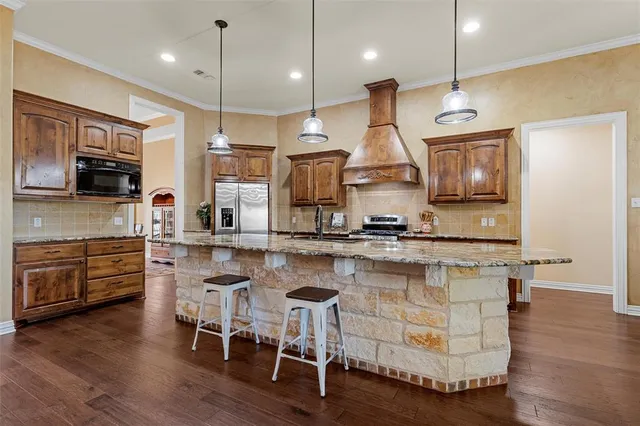 a kitchen with stainless steel appliances granite countertop wooden floors stove and cabinets