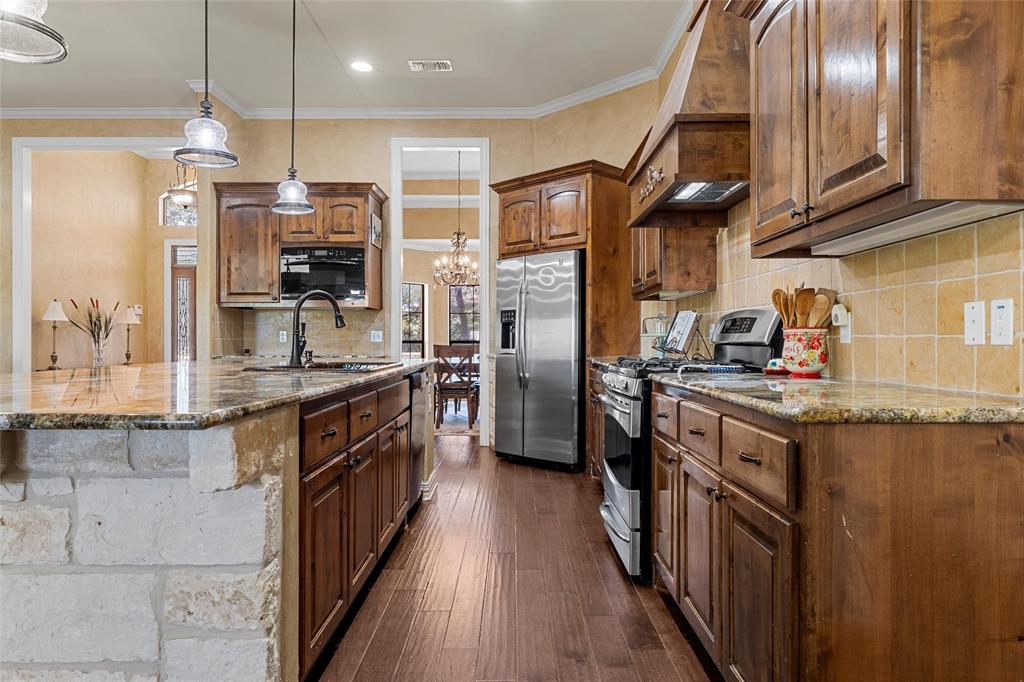 1125 Whispering Oaks China Spring, TX 76633 - Photo 7 of 39 Kitchen featuring dark stone countertops, hanging light fixtures, appliances with stainless steel finishes, ornamental molding, and decorative backsplash