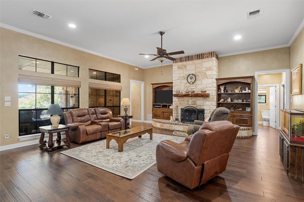 1125 Whispering Oaks China Spring, TX 76633 - Photo 10 of 39 Living area with crown molding, dark wood-style flooring, a ceiling fan, a fireplace, and recessed lighting