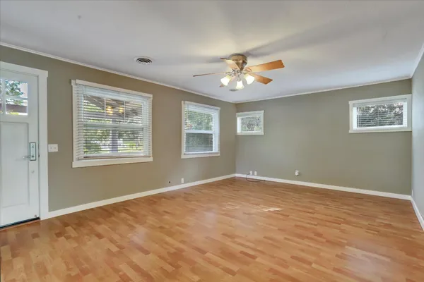a view of an empty room with a window and wooden floor