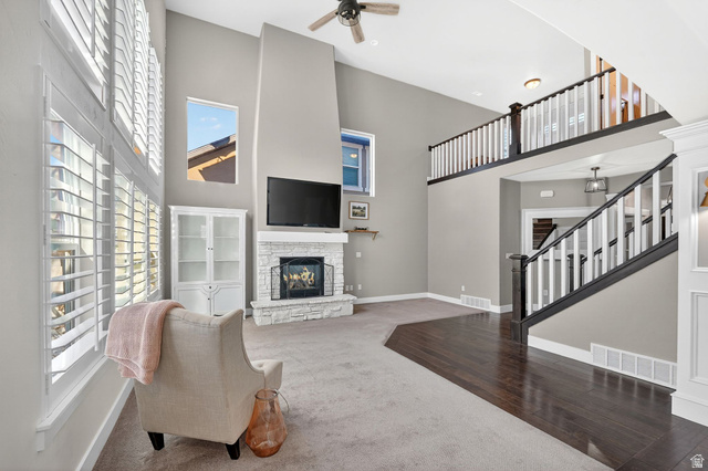 14714 South Bright Wood Road Herriman, UT 84096 - Photo 10 of 41 Living area with plenty of natural light, carpet floors, wood finished floors, a stone fireplace, and a high ceiling