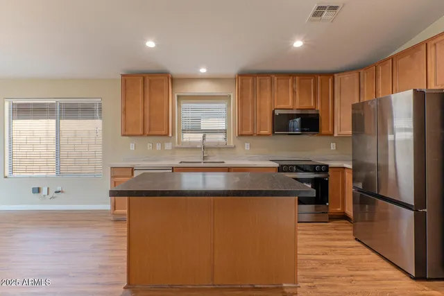 a kitchen with stainless steel appliances granite countertop a refrigerator a sink a stove a microwave and wooden cabinets