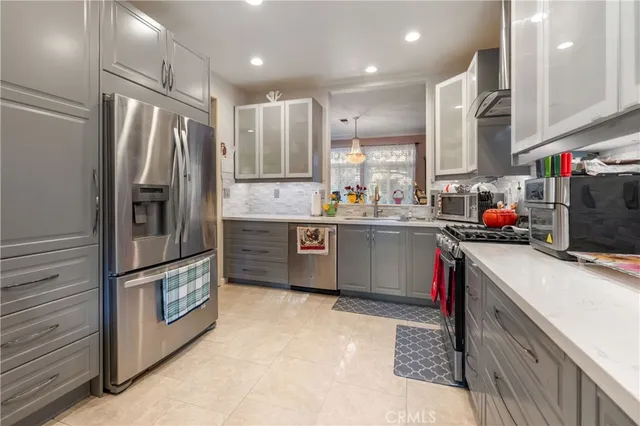 a kitchen with stainless steel appliances granite countertop a refrigerator a sink and a stove