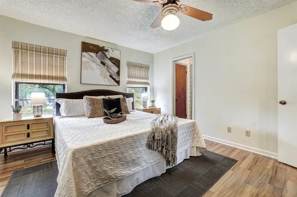 an empty room with wooden floor fan and windows