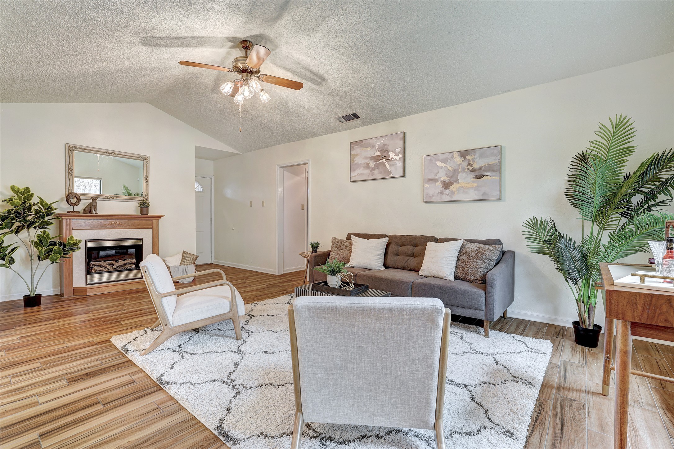 8606 Thunderbird Road, Unit A & B Austin, TX 78736 - Photo 4 of 29 Living area with ceiling fan, vaulted ceiling, a textured ceiling, a fireplace, and light wood-style floors