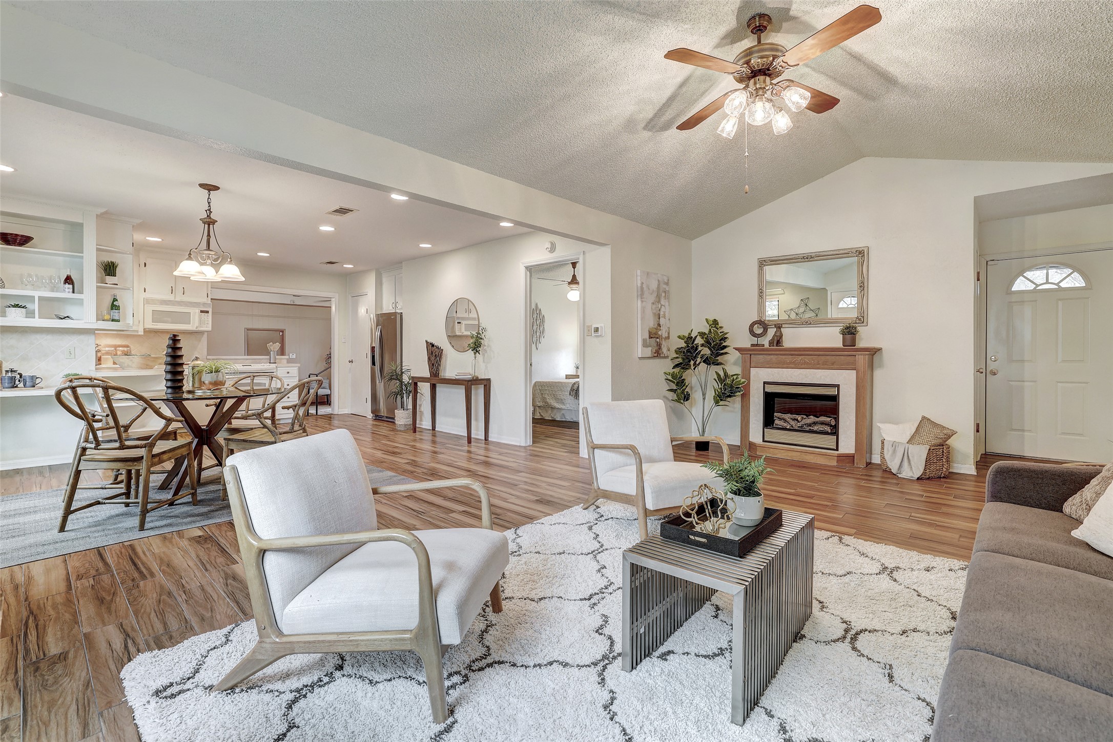 8606 Thunderbird Road, Unit A & B Austin, TX 78736 - Photo 5 of 29 Living room with light wood finished floors, a fireplace, ceiling fan, a textured ceiling, and vaulted ceiling