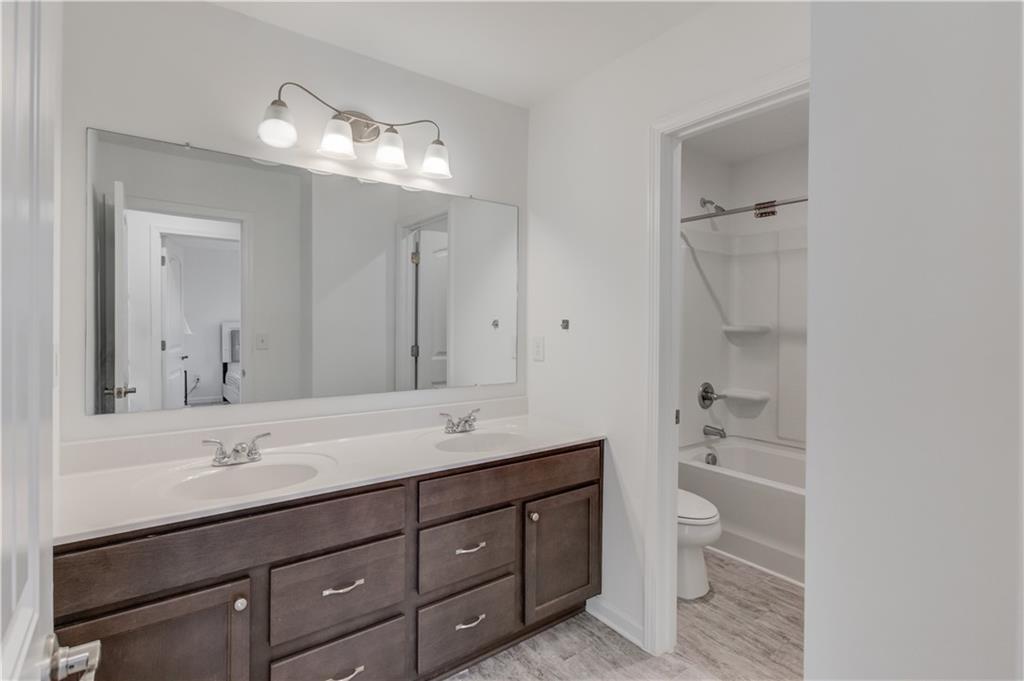 1810 Primrose Park Road Sugar Hill, GA 30518 - Photo 35 of 51 a bathroom with a double vanity sink a toilet and a mirror